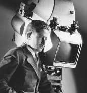 A Picture of William H. Daniels standing next to a camera